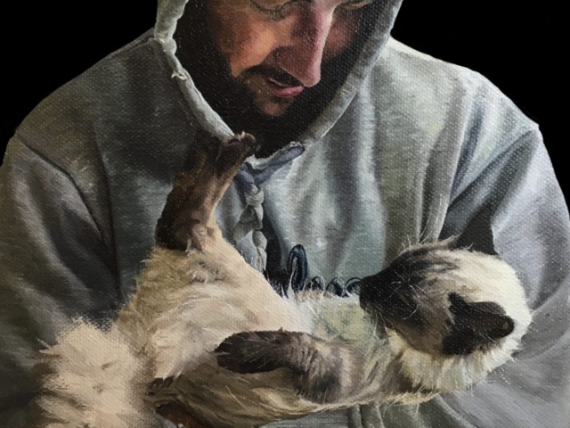 Portrait in oil paint on canvas of a man in a hooded sweatshirt holding a kitten in his arms.  Realism.